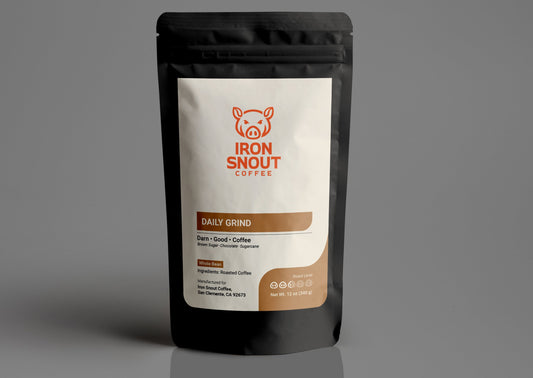 A sealed black coffee bag with the "Iron Snout Coffee" label and a pig logo, showcasing the "Daily Grind" blend.